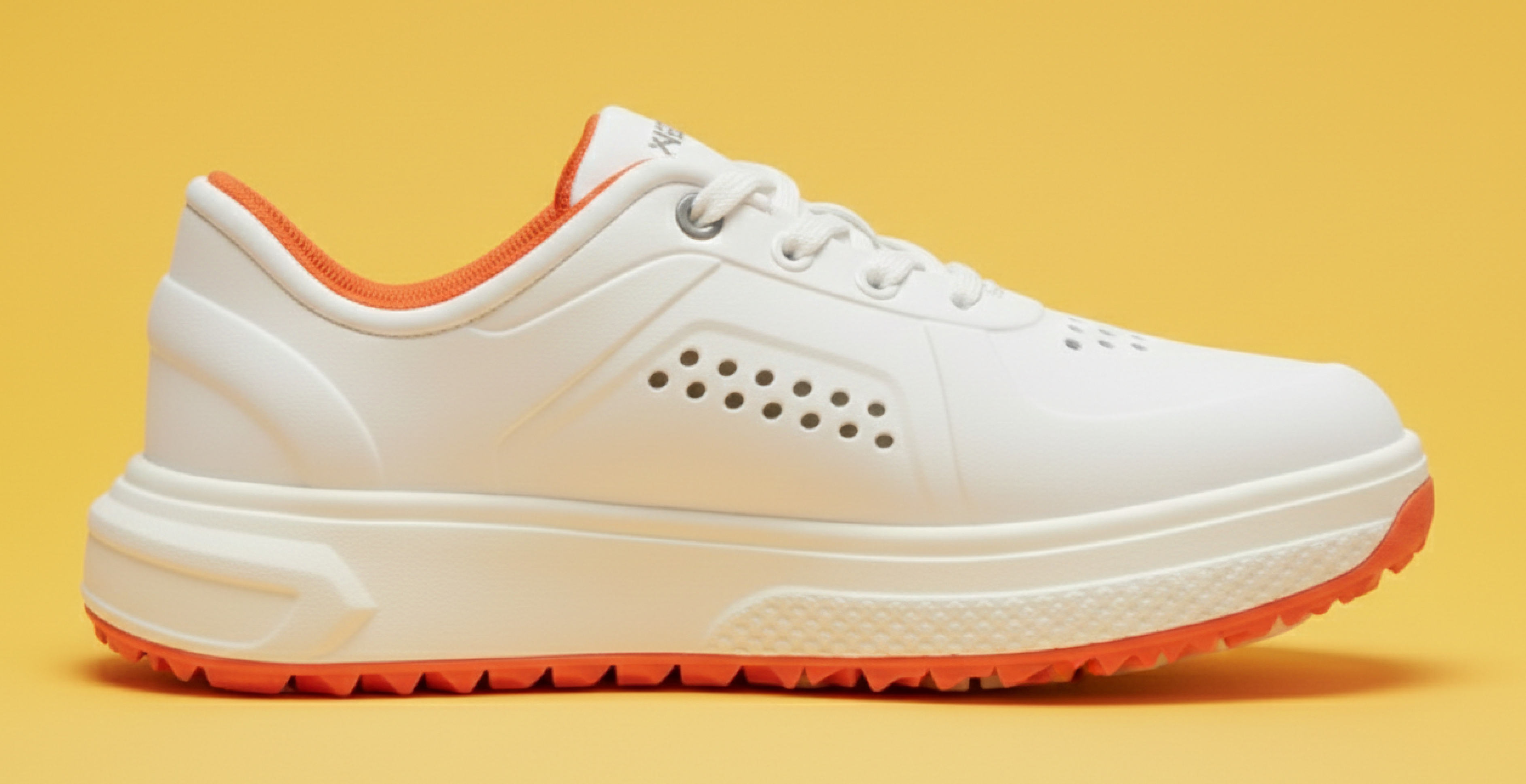 White golf sneaker with orange accents on a yellow background